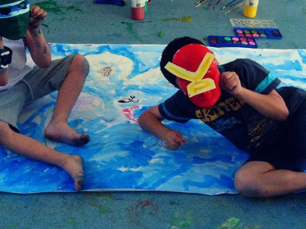 Children wearing masks they painted, on a big group painting
