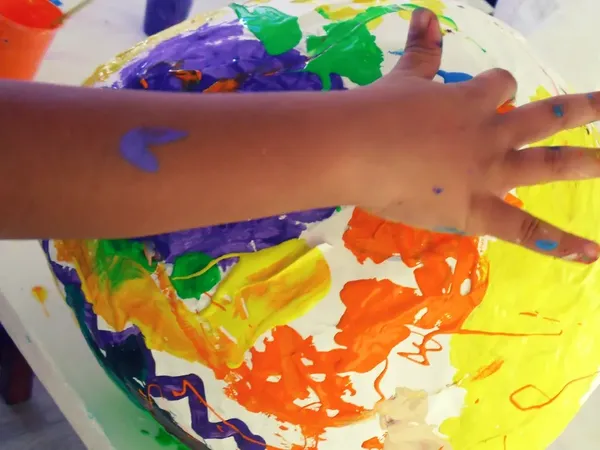 A hand painting a big papier-mâché globe